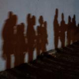 Shadows on a wall show asylum-seeking families as they queue up to be processed by the U.S. Border Patrol after crossing the Rio Grande River from Mexico, in Roma, Texas on August 12, 2021.