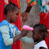 A girl uses a toy hairdryer as an infra-red thermometer on her friend as they play at Hann Bay on the eastern edge of Dakar, Senegal, April 12, 2021