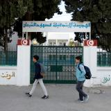 Children walk past the closed gates of a school in Tunisia
