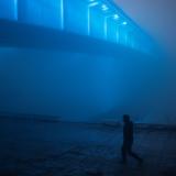 A man, illuminated by blue lights, walks under the Brankov bridge amidst dense fog and smog in Belgrade, Serbia, on January 15, 2020.