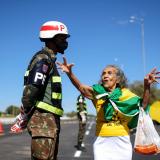 An old woman wrapped in Brazil's green and yellow flag confronts a Brazilian soldier in front of Brazil's Army Headquarters.