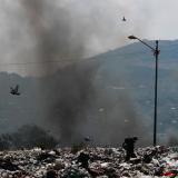 A man works on a garbage dump as black smoke rises in the background on the outskirts of the city, as the coronavirus disease (COVID-19) continues in Mexico City, Mexico, on April 27, 2020.