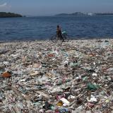 A man walks by plastic waste at a polluted beach on the banks of Guanabara Bay, in Rio de Janeiro, Brazil, on March 16, 2022.