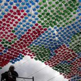 a museum worker, obscured by light, cleans next to an art installation made from repurposed, red, blue, and green bottles