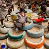 Children paint a pyramid of repurposed tires as part of a playground set up