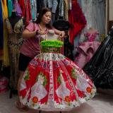 A shopkeeper arranges a pink and green formal dress made out of fabric  from recycled bottles