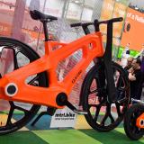 Two bright orange bicycles with black wheels are photographed on astroturf at an exhibition in Hanover, Germany