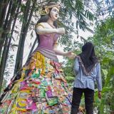 a male and female bystander look at a mock-up of the Indonesian goddess, Sri, that had been constructed from repurposed plastic waste