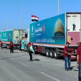 A line of trucks is seen surrounded by people waiting for the agreement. 