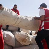 Five men seen loading a truck with large object wrapped in a white sheet.