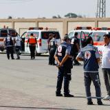 A group of men is seen standing beside a line of ambulances 
