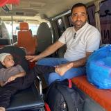 a boy sits on a gurney with a man watching over him in an ambulance.