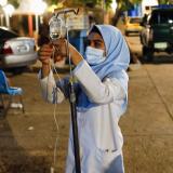 An Afghan nurse prepares serum drops for a victim of an earthquake in a hospital.