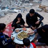 A Palestinian family eats their iftar meal they break their fast near the rubble of their destroyed house.