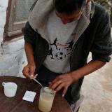 A man mixes his medication into a drink on a wooden table.