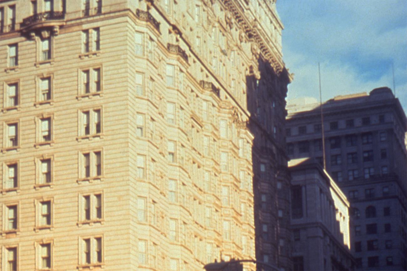  The photo shows an old, magnificent stone building against a bright blue sky. It’s a grainy photo, suggestive of a poor quality color film stock or a cheap camera. 