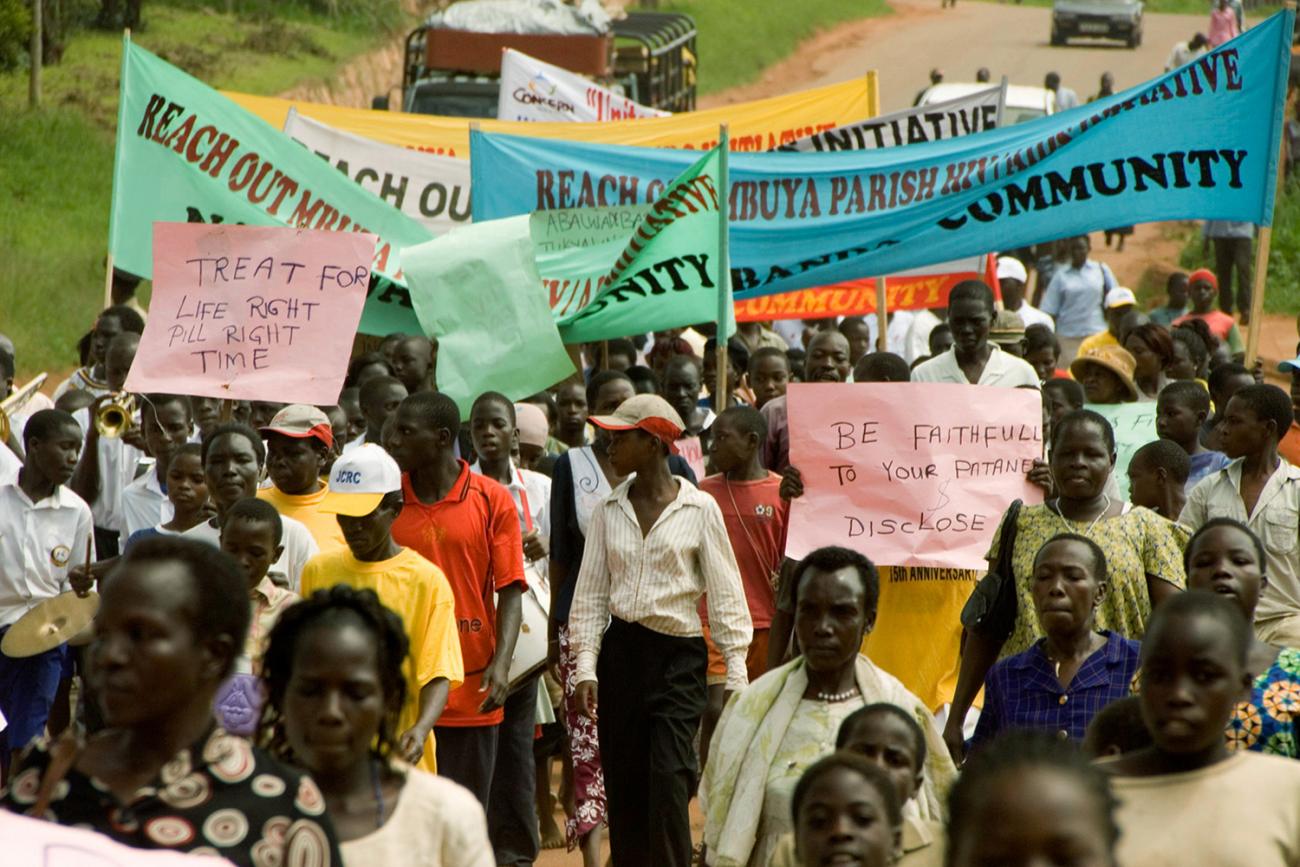  Picture shows dozens of protesters marching with banners and signs. 