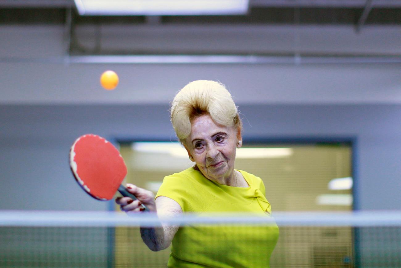 Picture shows Betty, who has an old fashioned 1950s-style hairdo, swinging her paddle at a ball. 