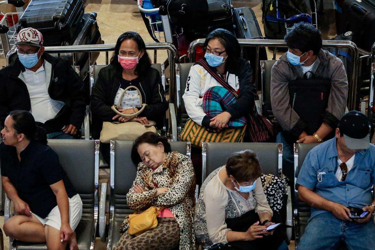 The photo shows people sacked out in airport chairs, some asleep, some on their cell phones, almost all wearing masks. 