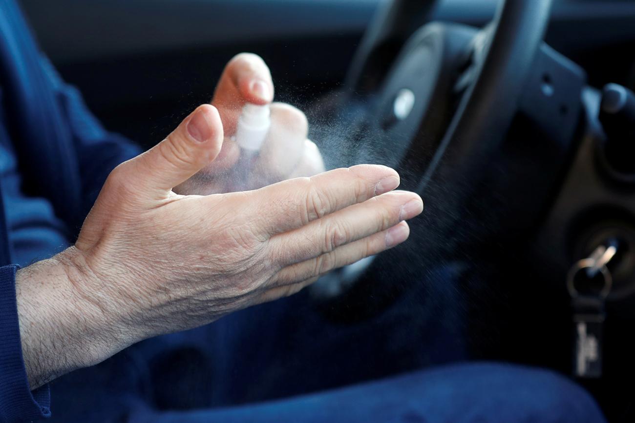 The image is a close-up of the cabbie washing his hands inside his vehicle. 