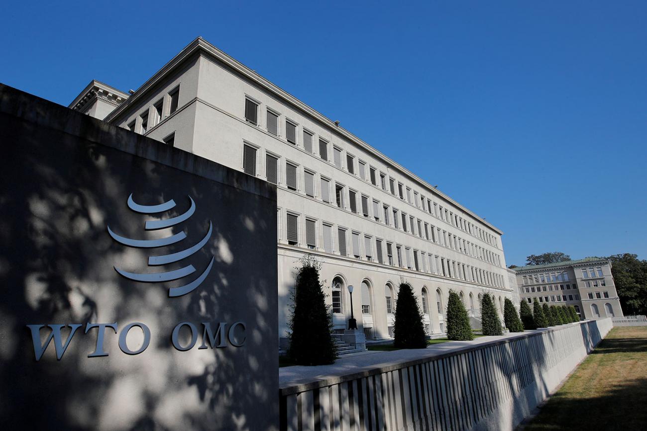 The photo shows a large stately building with the building's more modern sign in the foreground on a crisp, clear day. 