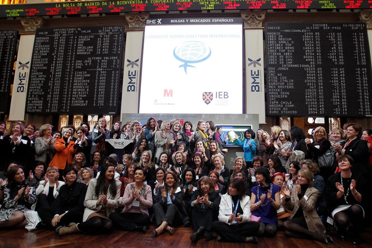 The picture shows a number of business women posing for a group photo. 