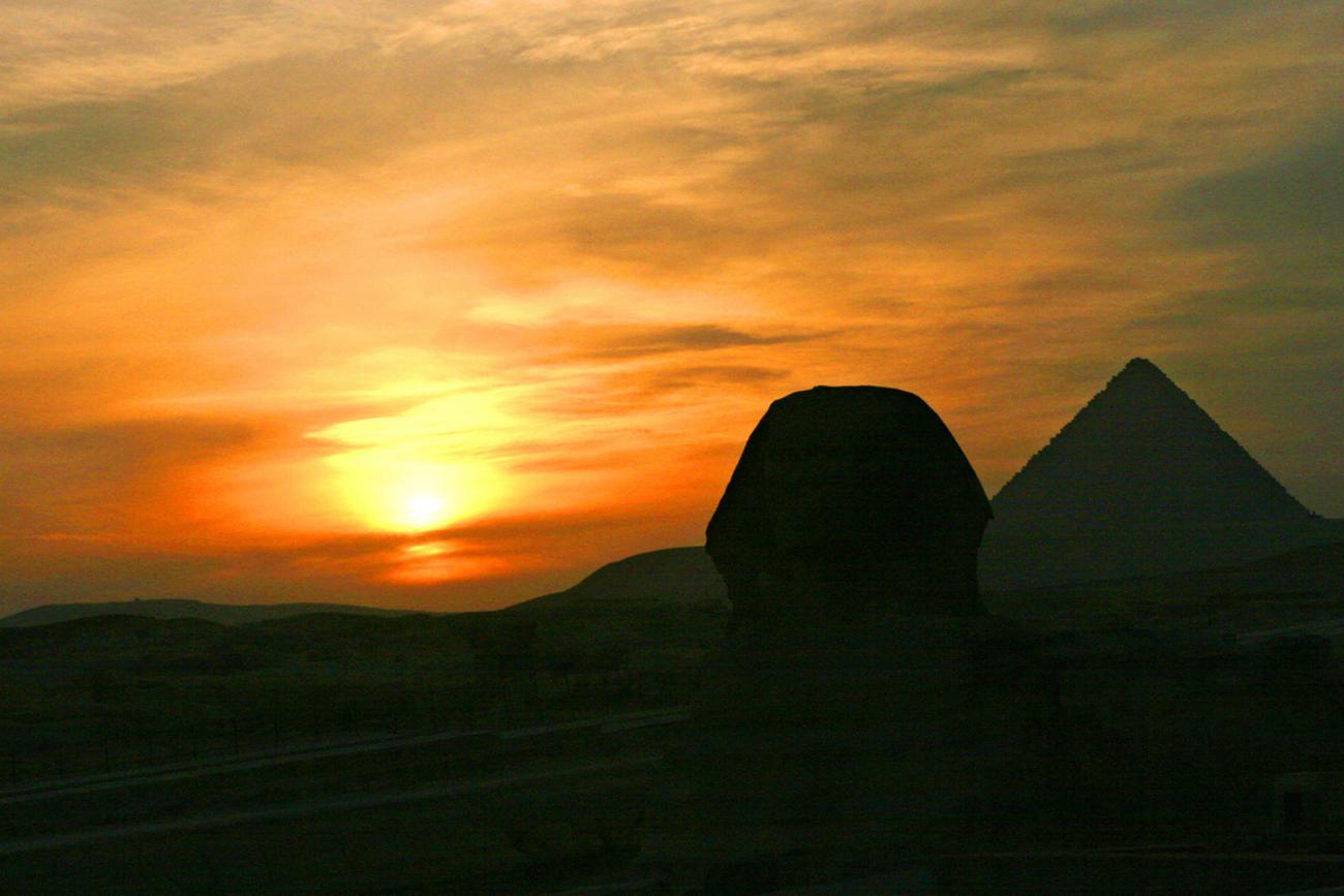 The photo shows a stunning sunset behind the pyramids. 