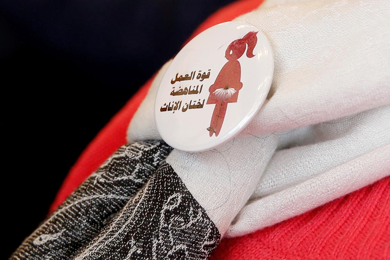 The image shows a button with Arabic script and the likeness of a girl on it. 