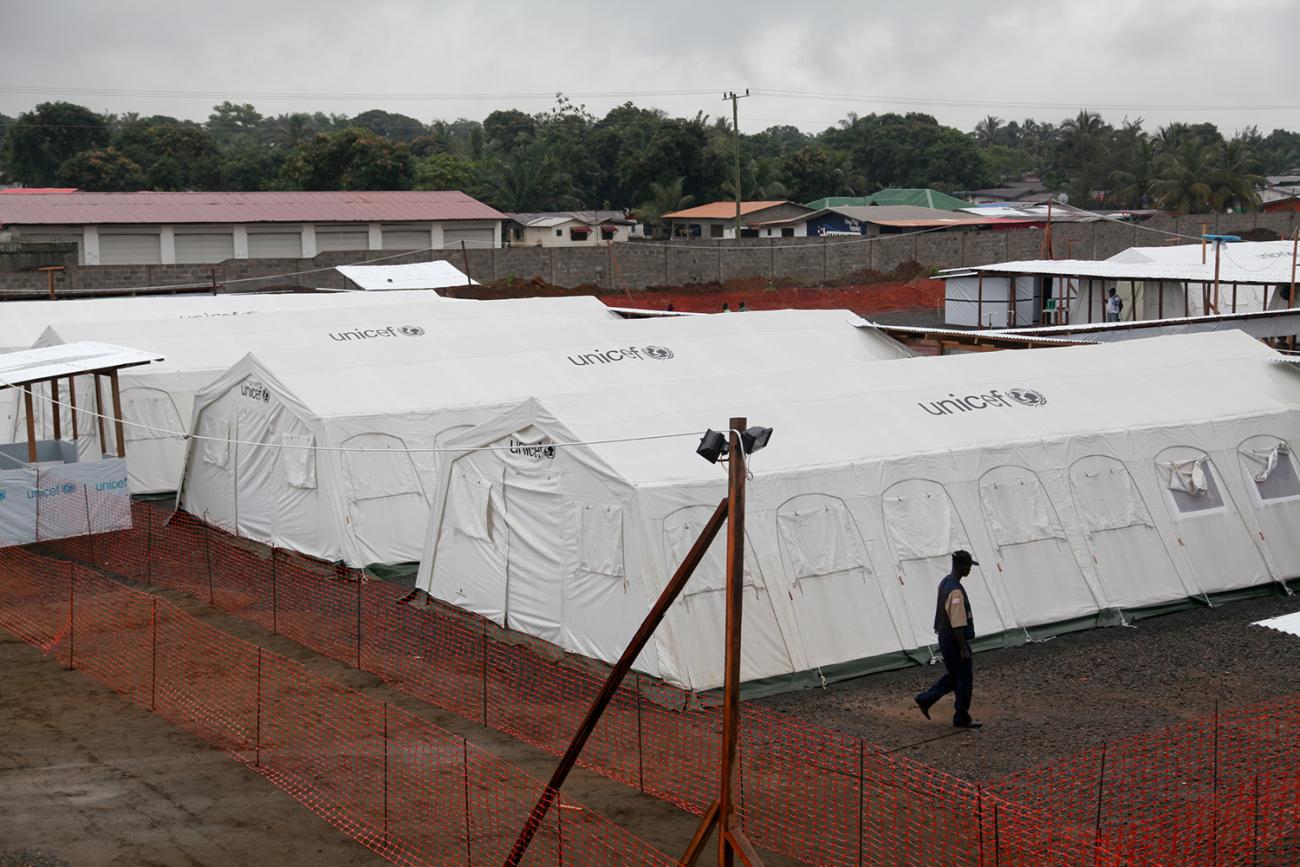 In the photo, a worker walks past one of several newly erected white tents. 