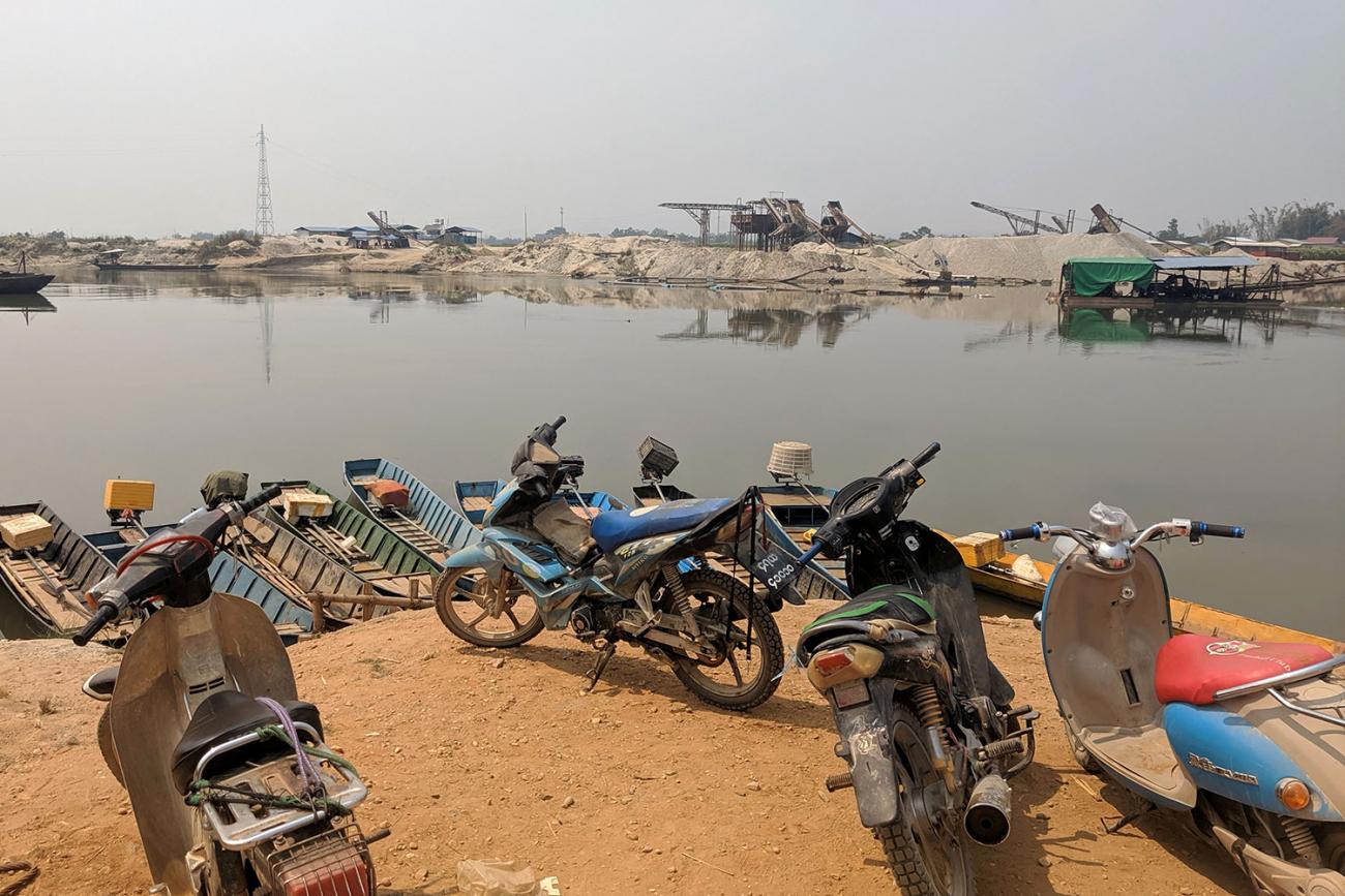 The photo shows an areae looking across a body of water with a number of motorbikes parked in the foreground. 