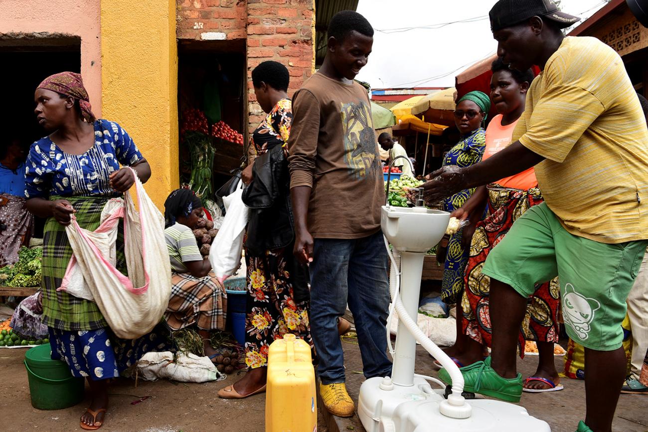 The picture shows a crowded scene with a man washing his hands 