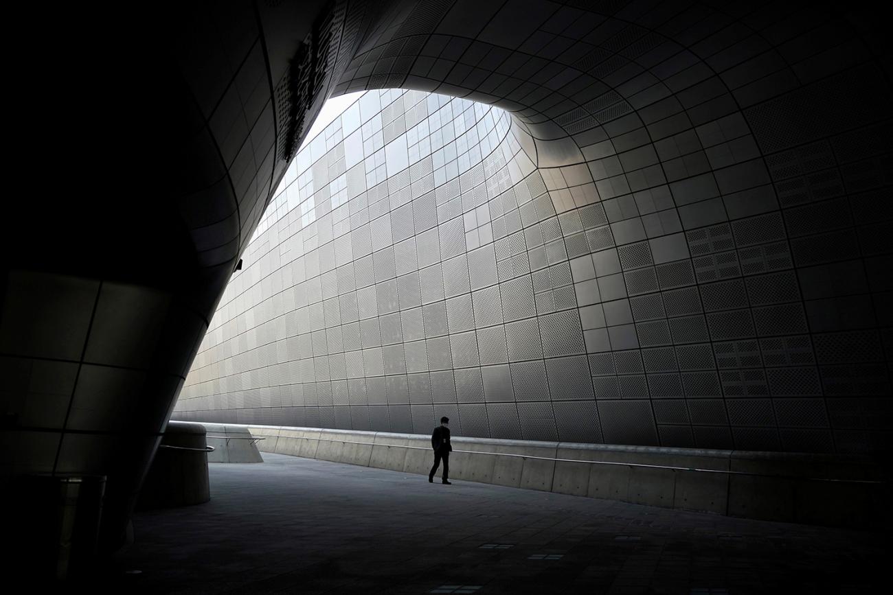 The image shows the tiny figure of a person walking along a huge corridor all by himself.