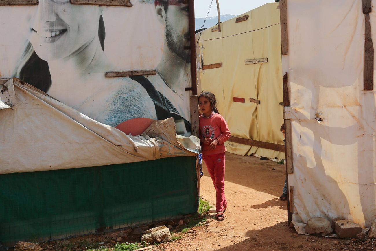 Picture shows a young girl in a pink outfit in between rows of temporary tented structures. 