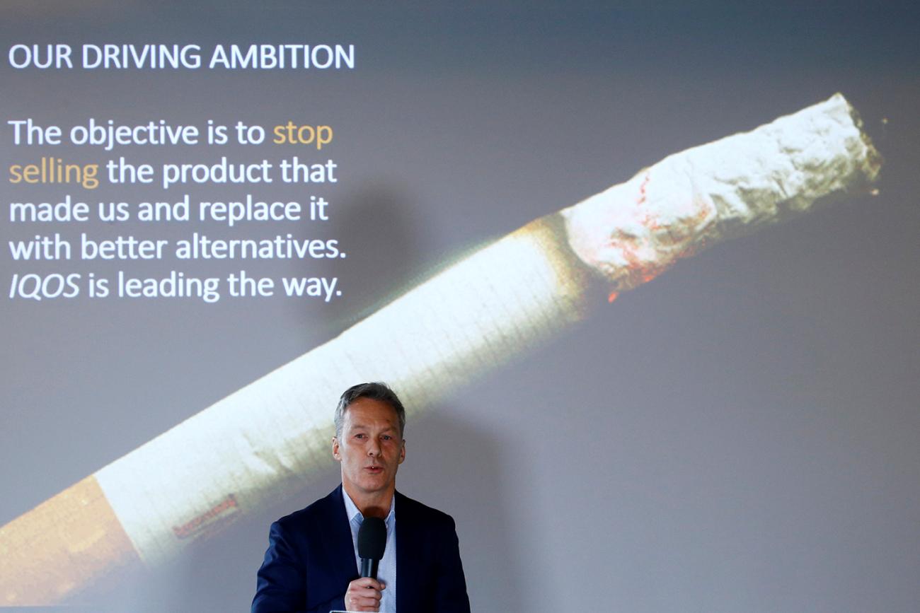 The executive stands in front of a screen with a large cigarette burning and the promise that the company's ambition is to stop selling cigarettes.