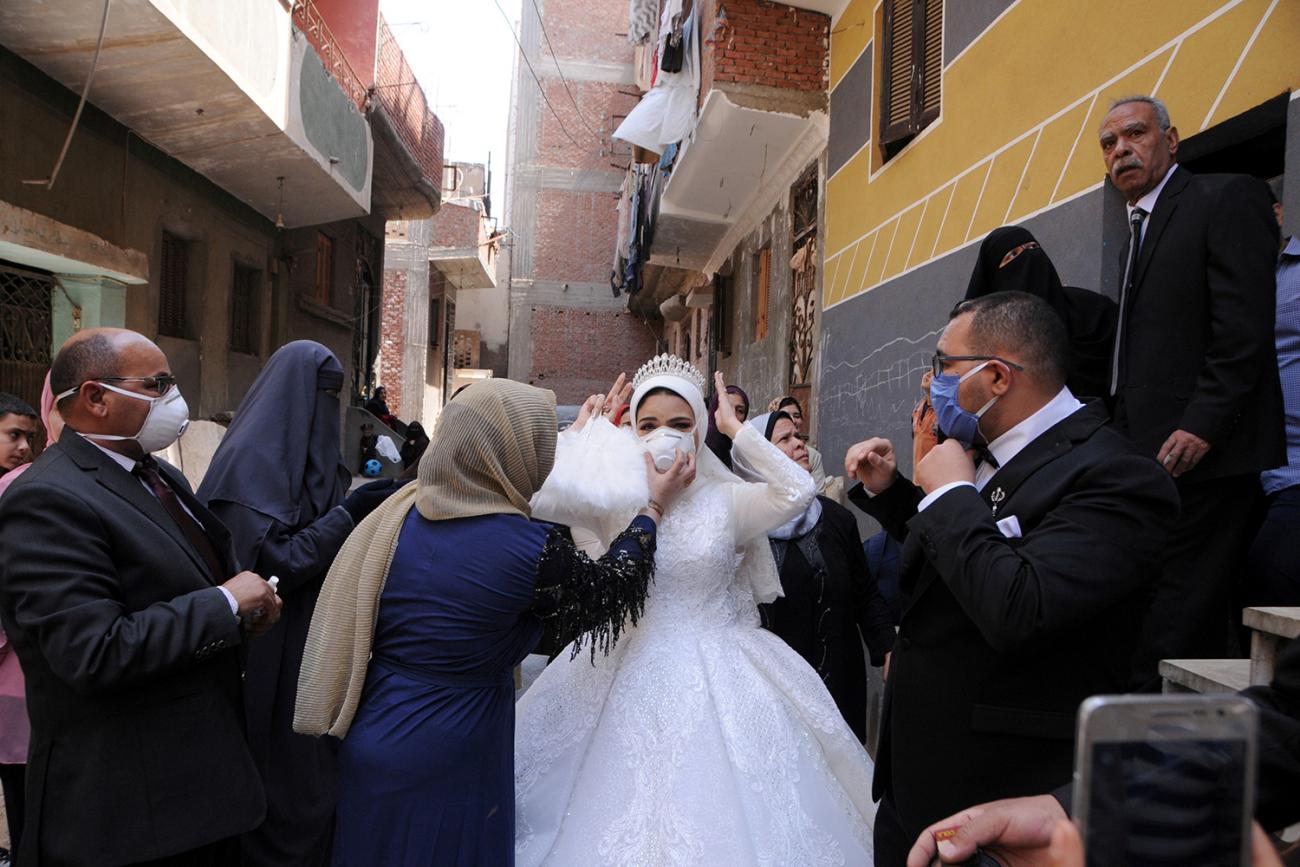 The photo shows bride and groom surrounded by people wearing masks. Picture taken April 16, 2020. 