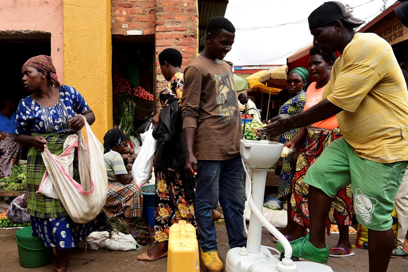 The picture shows a crowded scene with a man washing his hands 