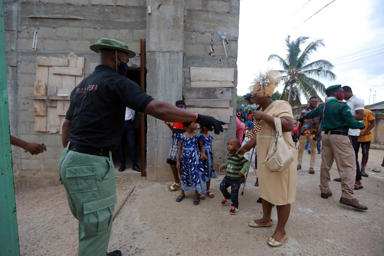 The photo shows a guard outside a church speaking with people waiting to enter. 