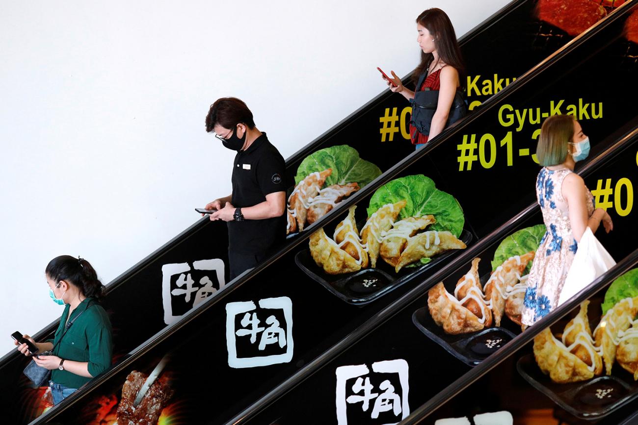 The photo shows two escalators from the side with people going variously up and down them. 