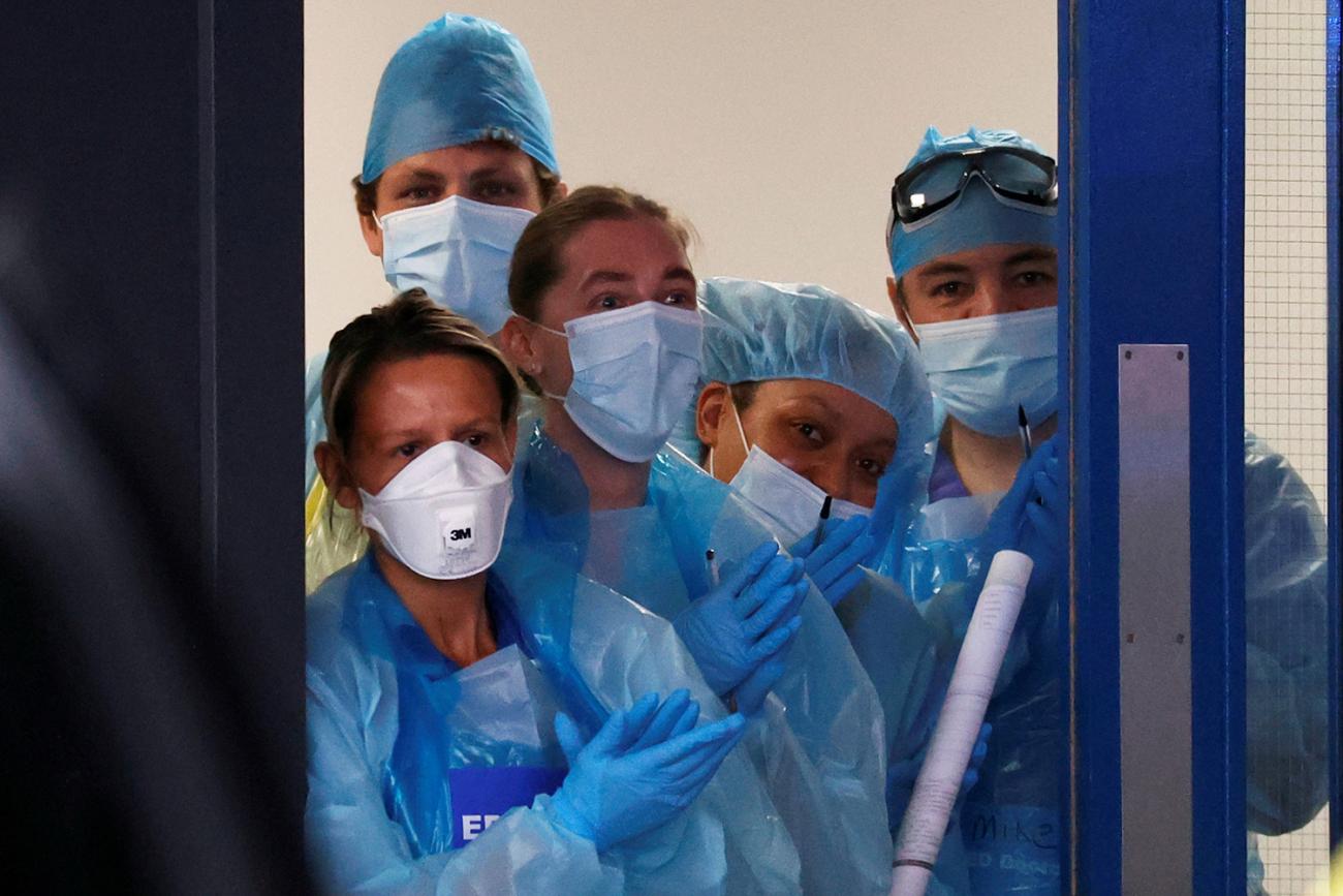 The photo shows several health workers in protective gear. 