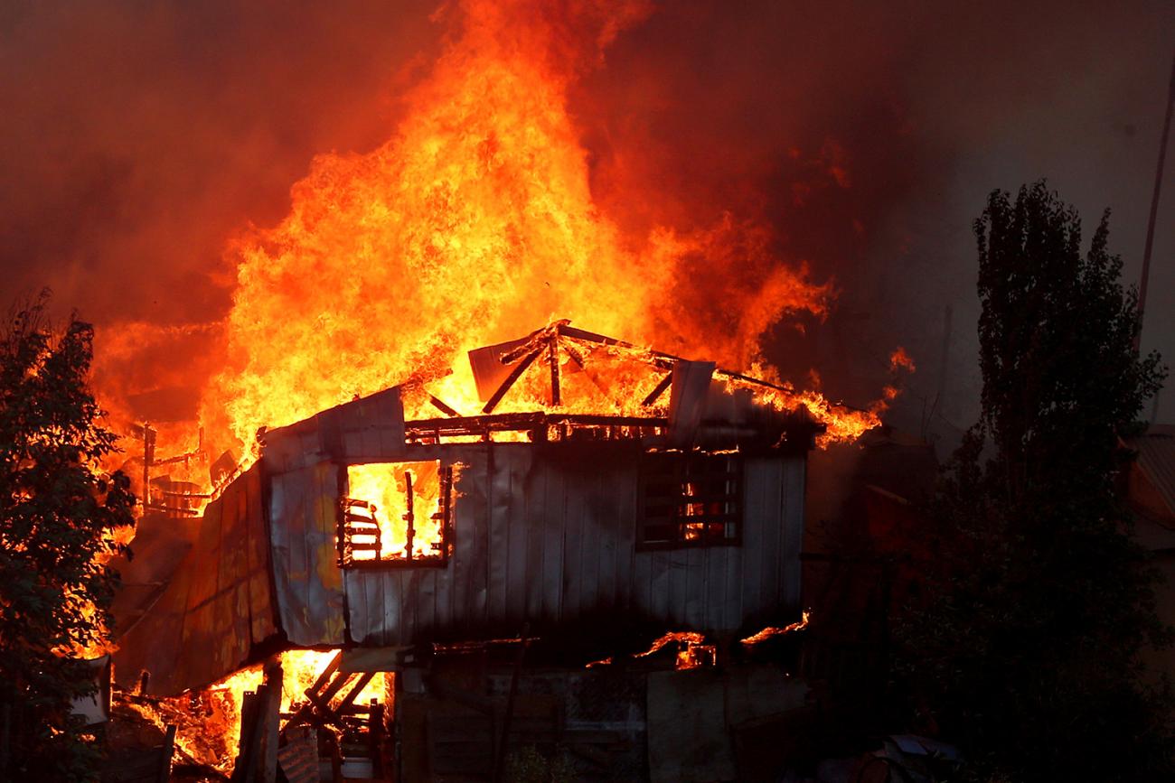 The photo shows a house engulfed in flames. 