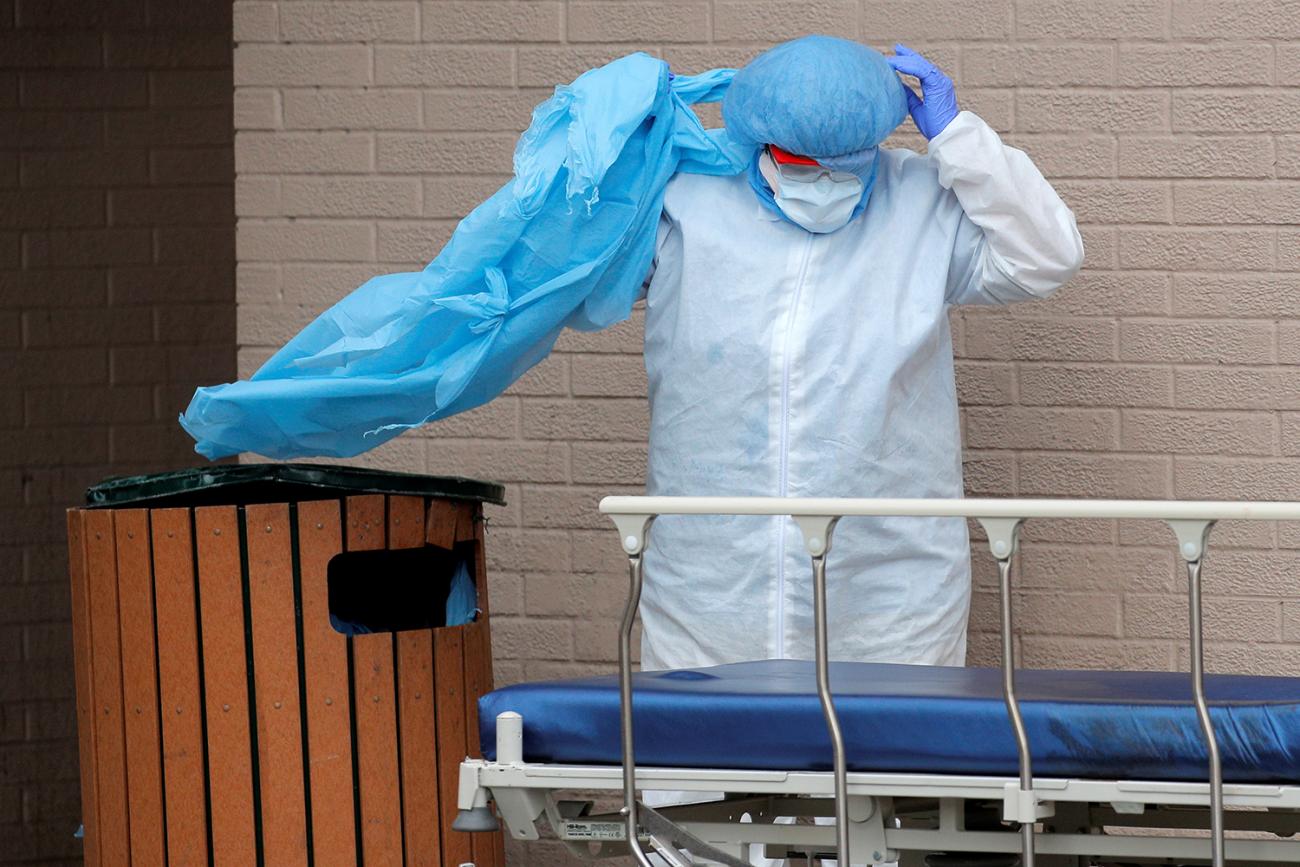 The photo shows the worker with an empty gurney taking off his PPE. 