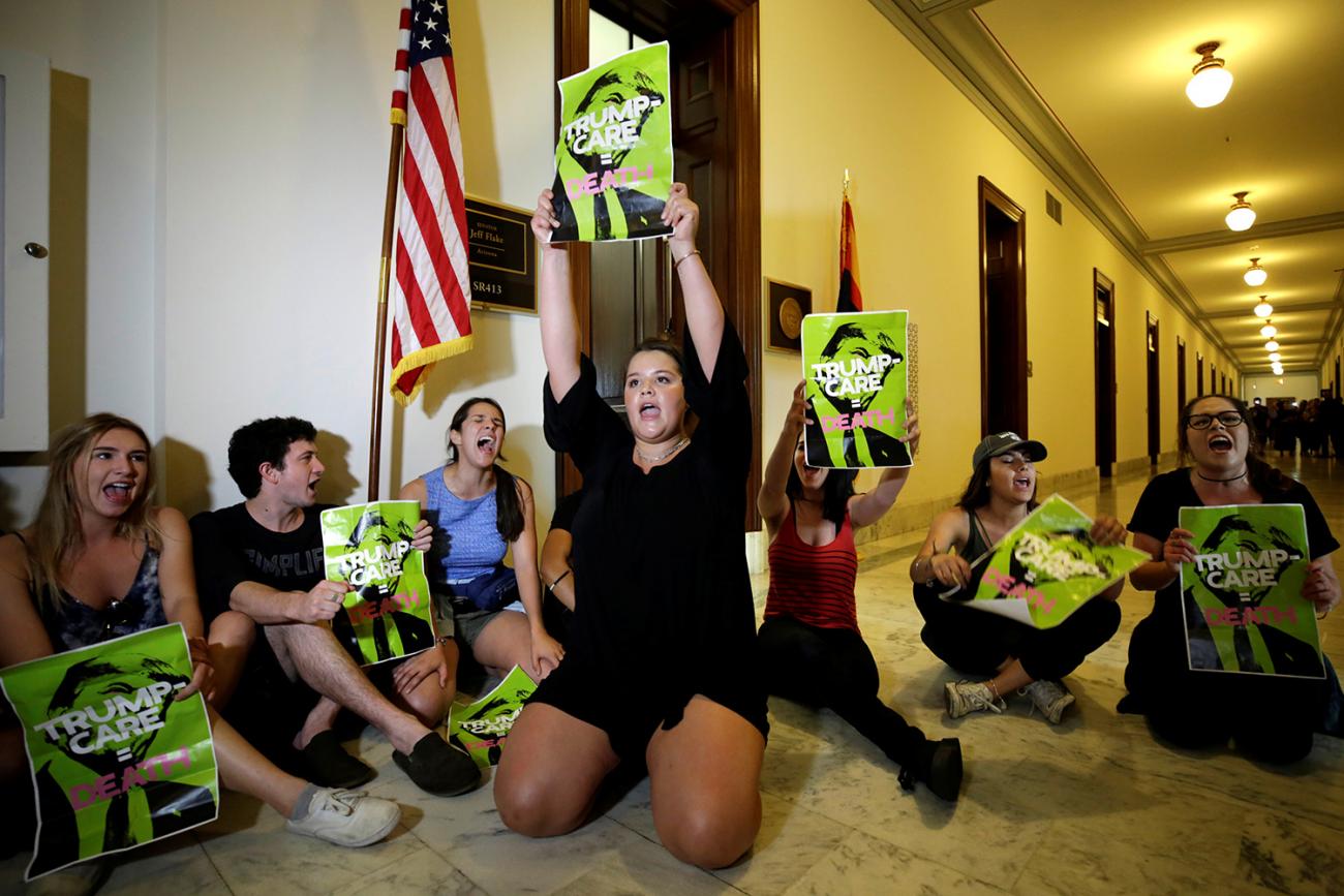 The photo shows a number of protesters staging a sit-in on the floor of a hallway in the senate building. 