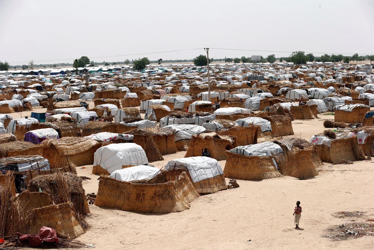 The photo shows a small girl in the foreground against the backdrop of a massive camp. 