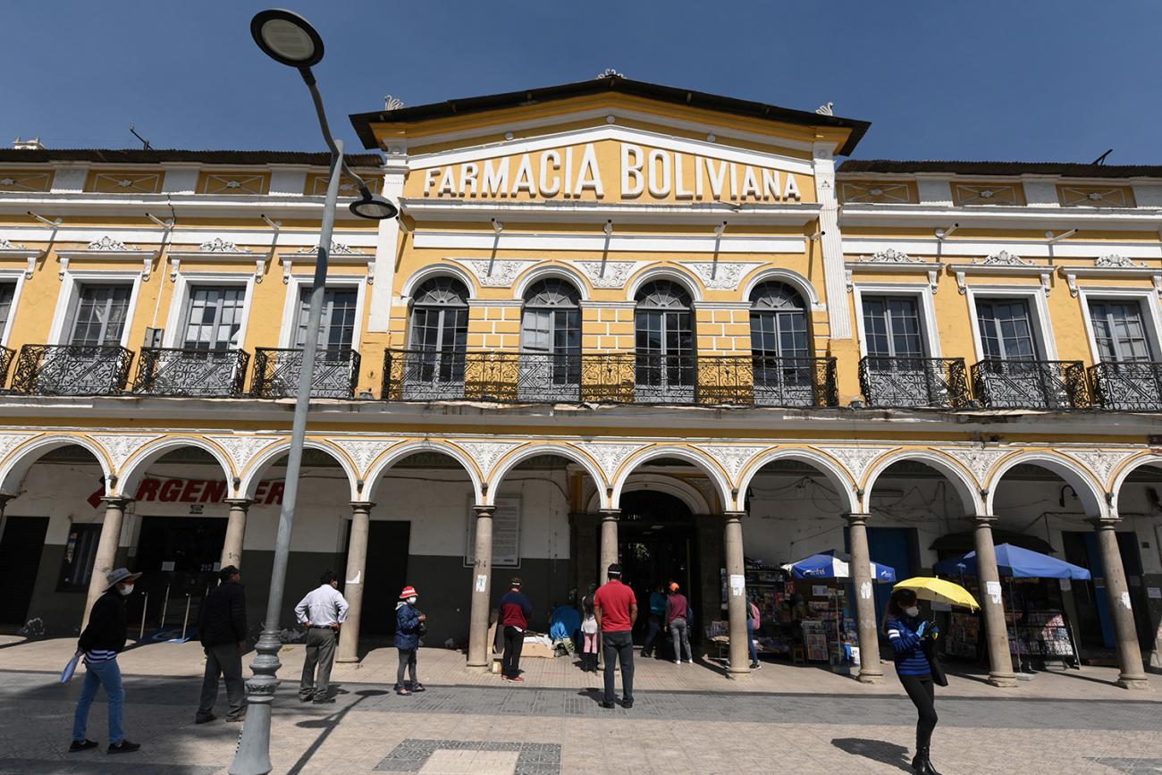 The photo shows a large building with a line of people out front. 