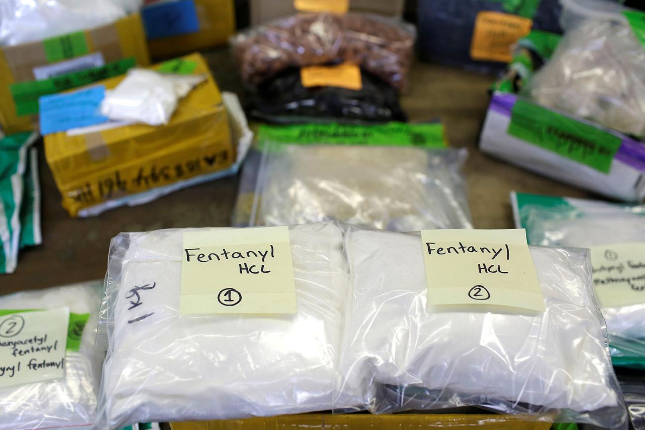 Picture shows several large clear plastic bags labeled fentanyl stacked on a table. 
