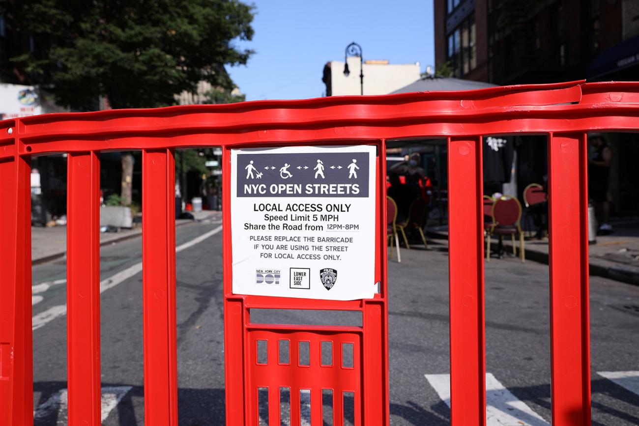 The photo shows a street with a big red barricade in the foreground.