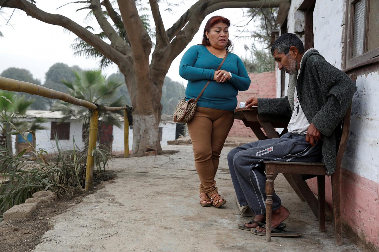 The photo shows the worker standing while the patient is seated in an outdoor setting. 