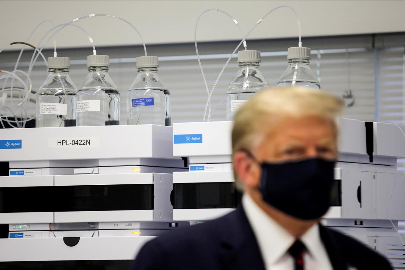 The photo shows the president wearing a mask in front of a fancy piece of equipment. 