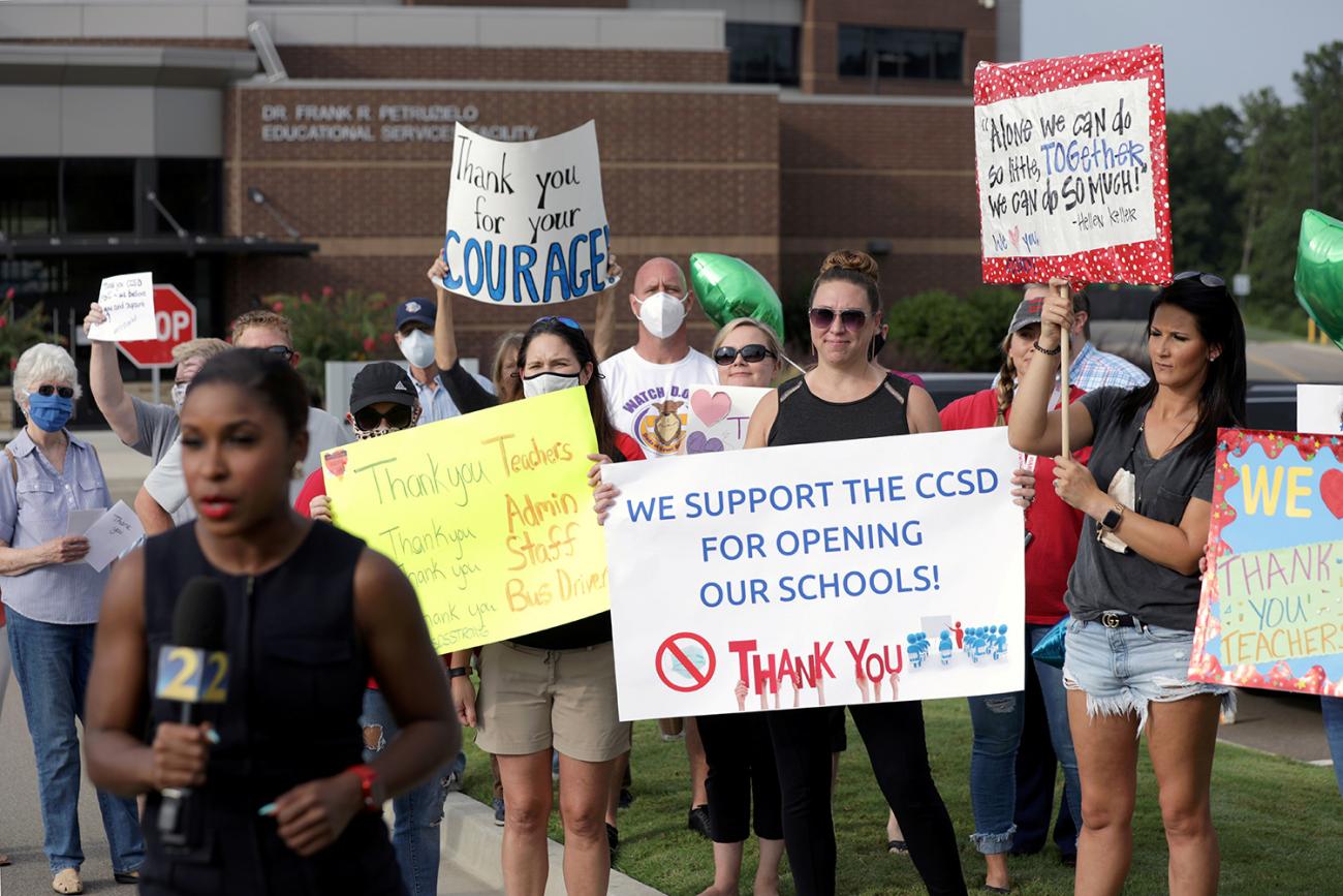 The photo shows a large crowd of women protesting and holding handmade signs.