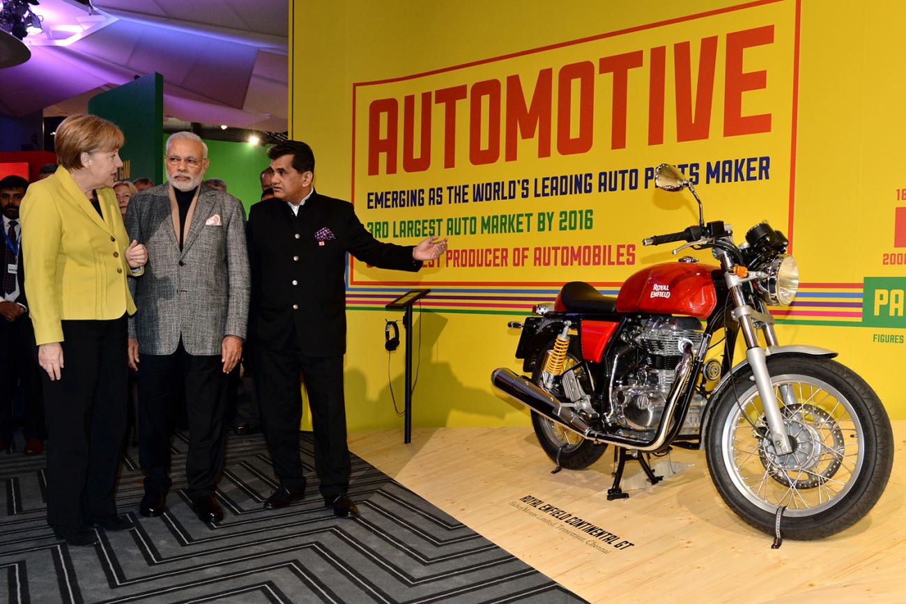 The photo shows the three political leaders at a display with a huge motorcycle.